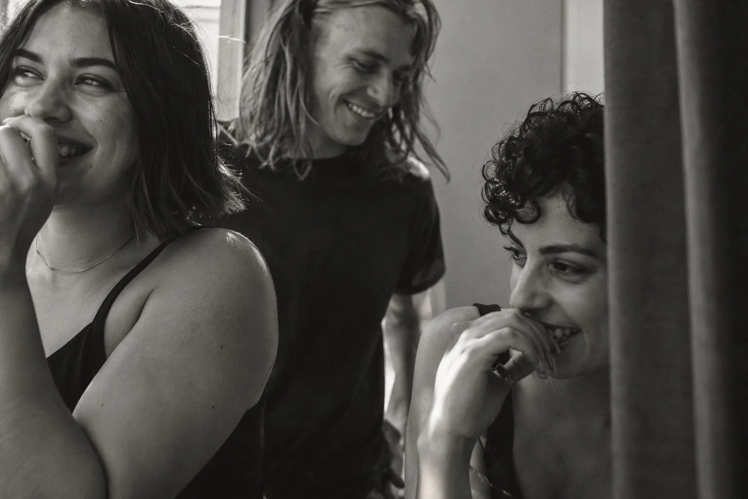 Friends laughing next to a fitting room curtain, in black and white