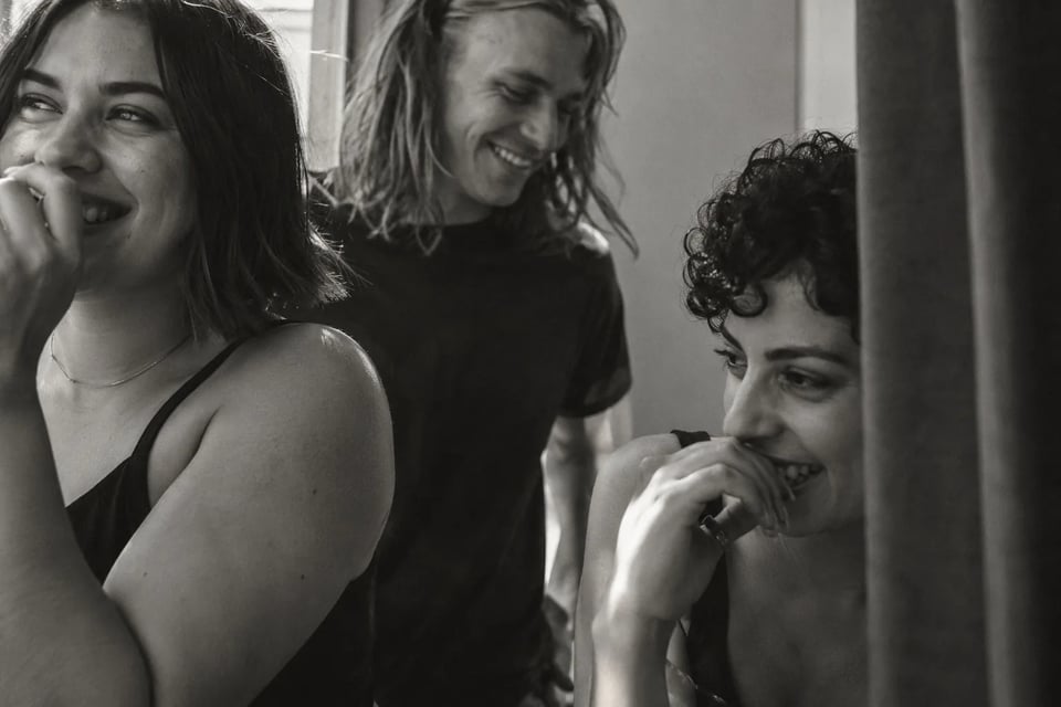 Friends laughing next to a fitting room curtain, in black and white