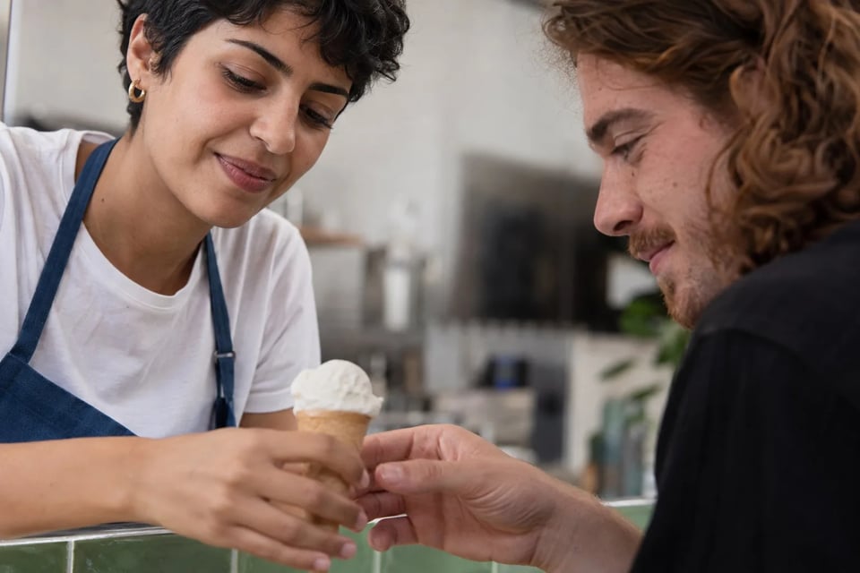 Un serveur remet un cornet de glace par-dessus le comptoir